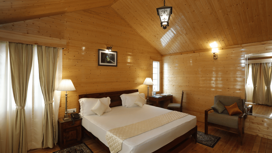 A well-lit bedroom with double bed, armchairs, and curtains drawn - Digantaa Resorts in Mukteshwar
